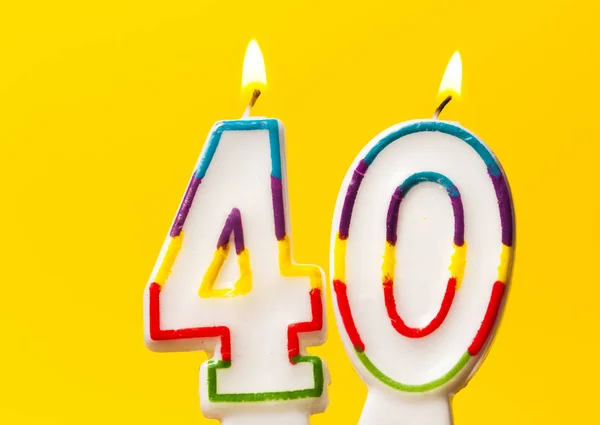 Number 40 birthday celebration candle against a bright yellow ba — Stock Photo, Image