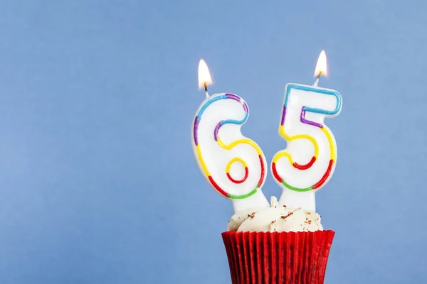 Number 65 birthday candle in a cupcake against a blue background — Stock Photo, Image