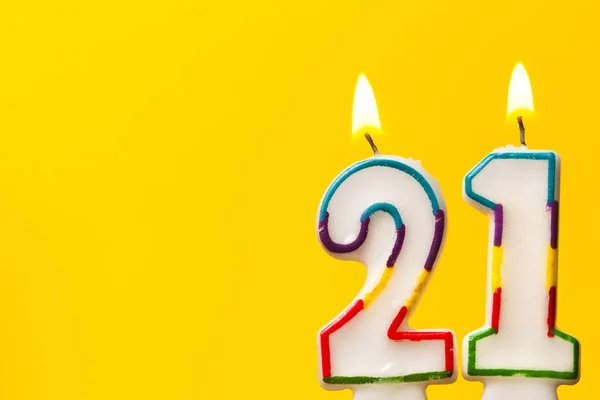 Número 21 aniversário celebração vela contra um ba amarelo brilhante — Fotografia de Stock