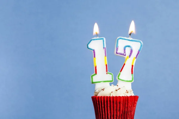 Número 17 vela de aniversário em um cupcake contra um fundo azul — Fotografia de Stock