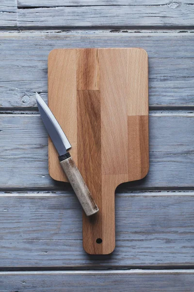 Tabla de cortar madera y cuchillo sobre un fondo rústico de madera —  Fotos de Stock