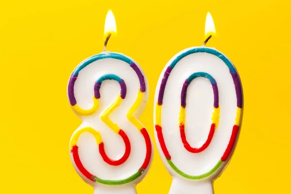Antal 30 födelsedagsfirande ljus mot en ljusgul ba — Stockfoto