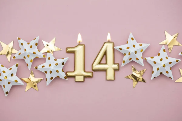 Vela dorada número 14 y estrellas sobre fondo rosa pastel —  Fotos de Stock
