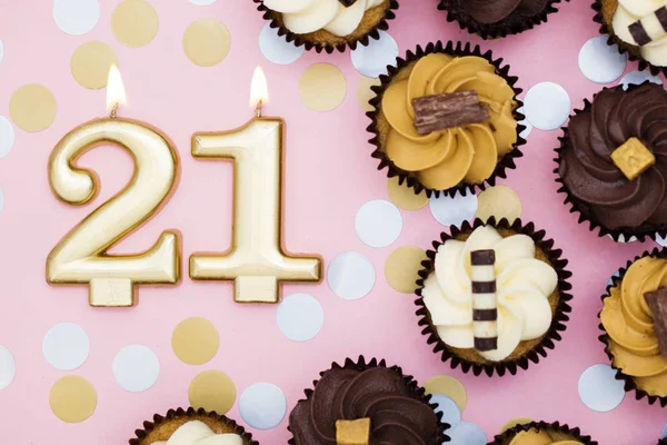 Nummer 21 guld ljus med cupcakes mot en pastell rosa bakgr — Stockfoto