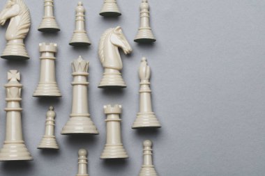 Gri bir arka plan üzerinde satranç oyunu parçaları. Strateji kavramı