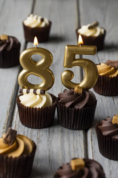 Cupcakes de cumpleaños de celebración número 85 sobre un fondo de madera —  Fotos de Stock