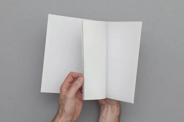 Um maquiador de livros. Mão masculina segurando livro em branco . — Fotografia de Stock