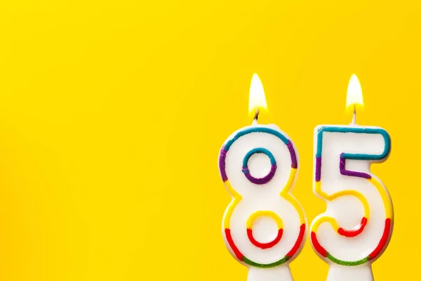 Number 85 birthday celebration candle against a bright yellow ba — Stock Photo, Image