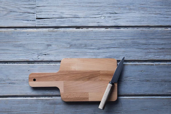 Tabla de cortar madera y cuchillo sobre un fondo rústico de madera —  Fotos de Stock