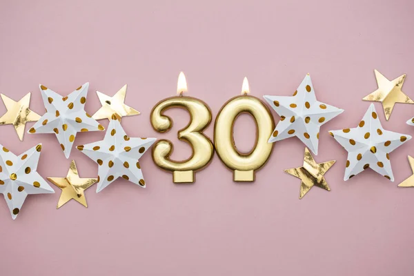 Číslo 30 zlatá svíčka a hvězdy na pastelově růžovém pozadí — Stock fotografie