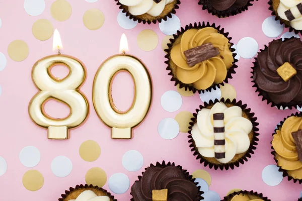 Vela dorada número 80 con cupcakes contra un fondo rosa pastel —  Fotos de Stock