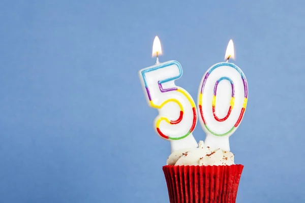 在蓝色背景的纸杯蛋糕中，有50号生日蜡烛 — 图库照片