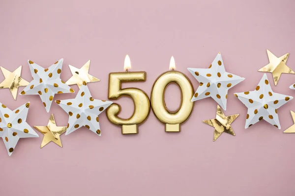Vela dorada número 50 y estrellas sobre fondo rosa pastel —  Fotos de Stock