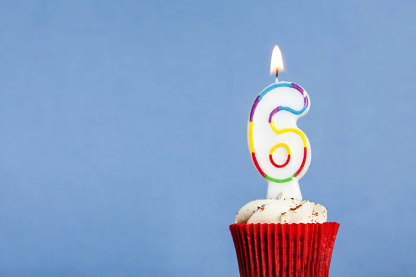 Número 6 vela de aniversário em um cupcake contra um fundo azul — Fotografia de Stock