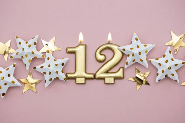 Number 12 gold candle and stars on a pastel pink background — Stock Photo, Image