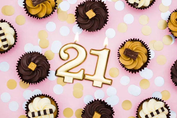Nummer 21 guld ljus med cupcakes mot en pastell rosa bakgr — Stockfoto