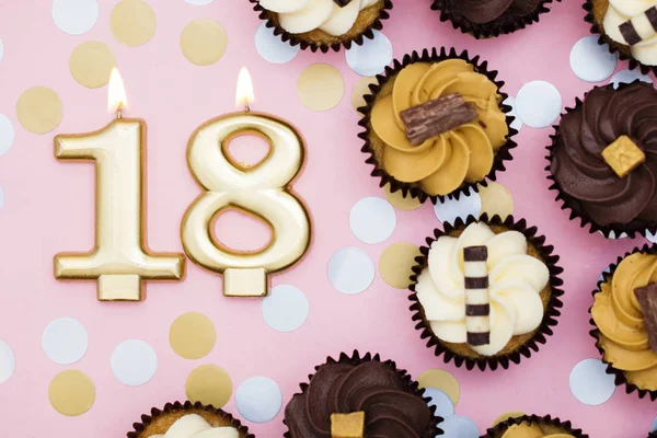 Nummer 18 Goldkerze mit Cupcakes vor pastellrosa Backgr — Stockfoto