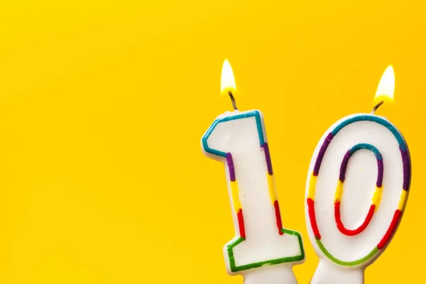 Свеча для празднования дня рождения номер 10 против ярко-желтой — стоковое фото