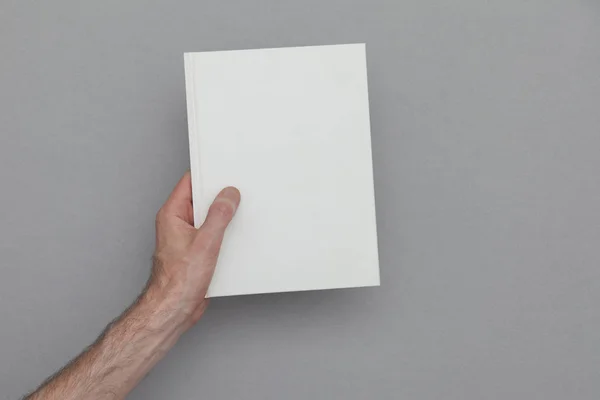 Male hand holding a closed book showing the book cover. Book Moc — Stock Photo, Image