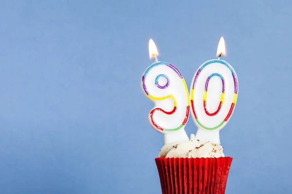 Número 90 vela de aniversário em um cupcake contra um fundo azul — Fotografia de Stock