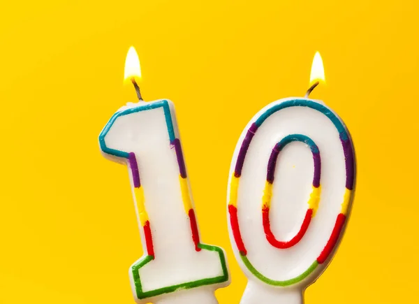 Número 10 vela celebração de aniversário contra um ba amarelo brilhante — Fotografia de Stock