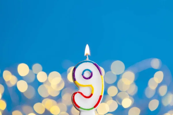 Oslavou číslo 9 narozeninová svíčka proti světlými světly a — Stock fotografie