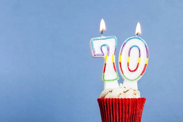 Número 70 vela de aniversário em um cupcake contra um fundo azul — Fotografia de Stock