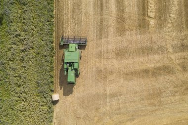 Bir çiftlik alanında yeşil bir birleştirme hasat makinesi üzerinde havadan görünümü