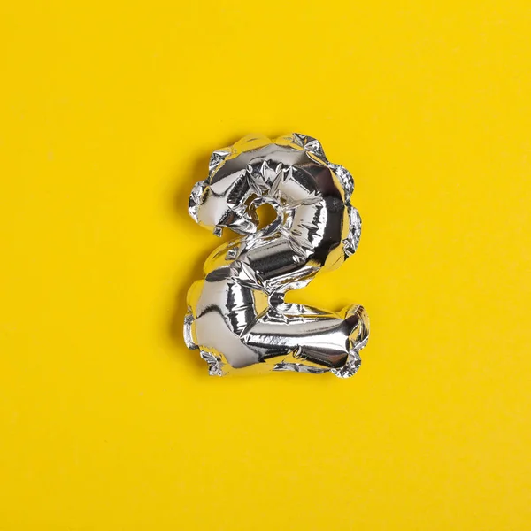 Silver foil number 2 celebration balloon on a bright yellow back — Stock Photo, Image