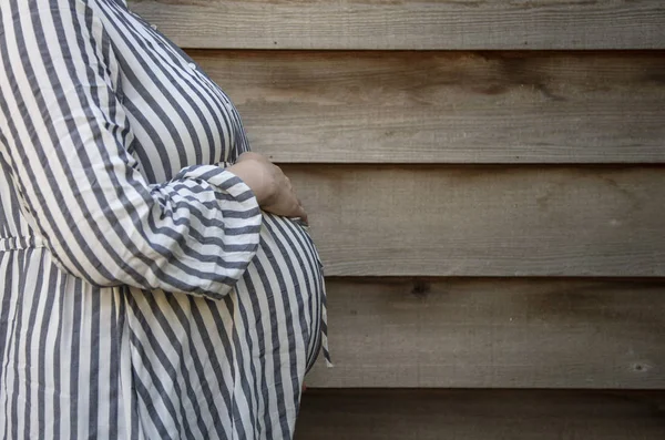 Těhotnou ženu, která držela dětskou bouli, stála proti obyčejným pozadím — Stock fotografie