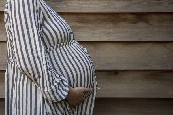 Una donna incinta che tiene il suo pancione in piedi su uno sfondo semplice — Foto Stock