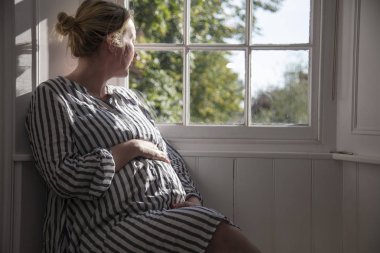 Pencerenin yanında oturan bir prgnant kadın