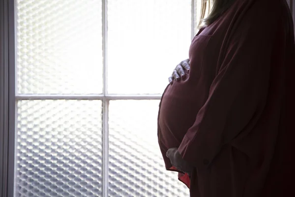 Silhouette di una donna prgnant in piedi davanti a una finestra — Foto Stock