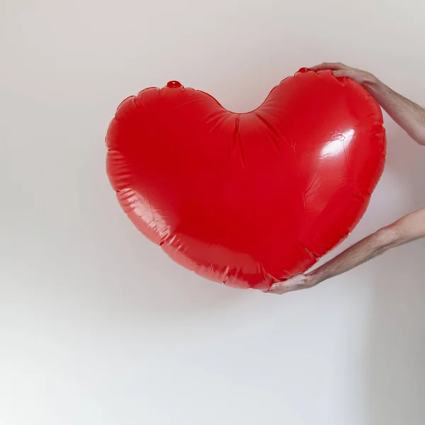 Mains tenant une grande forme de coeur gonflable — Photo
