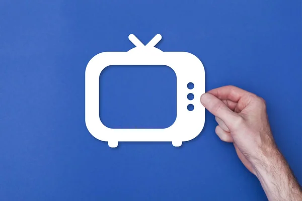 Mužská ruka držící televizní symbol na modré zadní gr — Stock fotografie