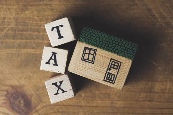 Domovní model s daňovým slovem vyrobený z dřevěných bloků. Finance v domácnosti — Stock fotografie