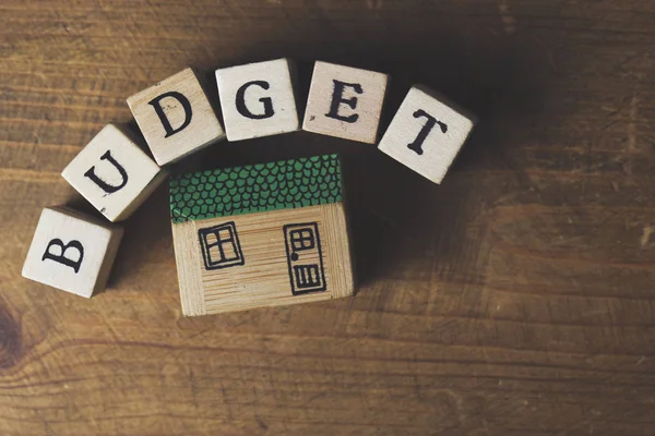 Home budget concept. Huis model met budget woord gemaakt van hout — Stockfoto