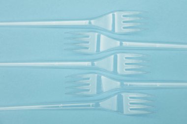 Plastik çatal mavi bir arka plan üzerinde düzenlenmiş. Plastik oldu