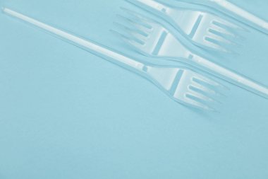 Plastik çatal mavi bir arka plan üzerinde düzenlenmiş. Plastik oldu