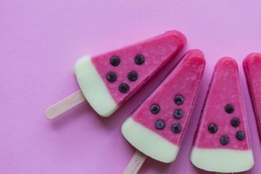 Karpuz şeklinde yaz buz lolly bir pastel pembe arka plan üzerinde