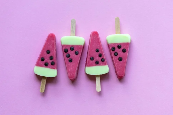 Watermelon shaped summer ice lolly on a pastel pink background
