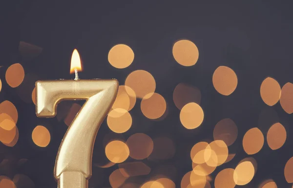 Vela de celebración número 7 de oro contra fondo de luz borrosa —  Fotos de Stock