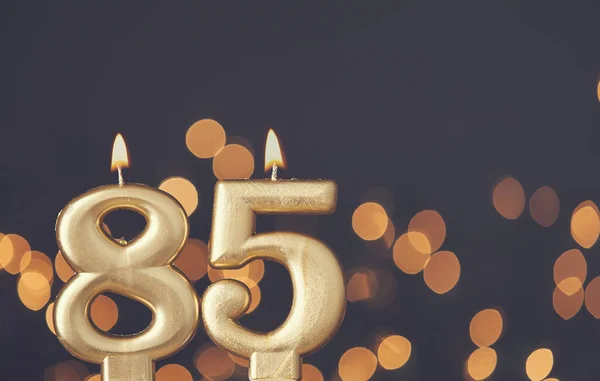 Arany szám 85 ünneplő gyertya ellen homályos fény háttérb — Stock Fotó