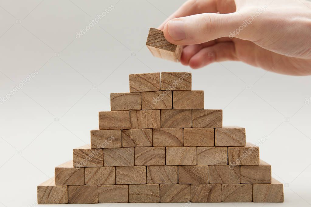 Male hand stacking wooden blocks. Business development and growt