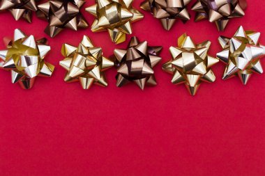 Kırmızı arka planda metalik hediye fiyonsu