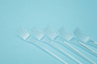 Plastik çatal mavi bir arka plan üzerinde düzenlenmiş. Plastik oldu