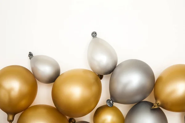 Gold and silver party celebration balloons on a plain background
