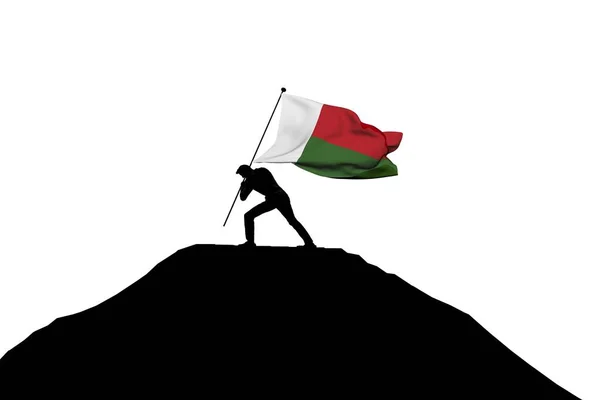 Madagaskar-Fahne wird von männlicher Silhouette in Berggipfel gedrückt — Stockfoto