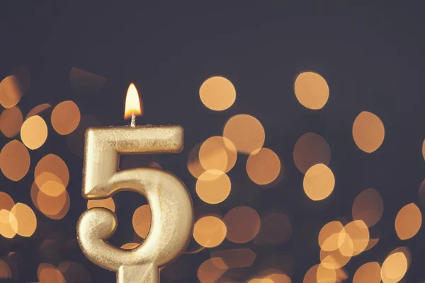 Zlaté číslo 5 oslava svíčky proti rozmazané světelné backgroun — Stock fotografie