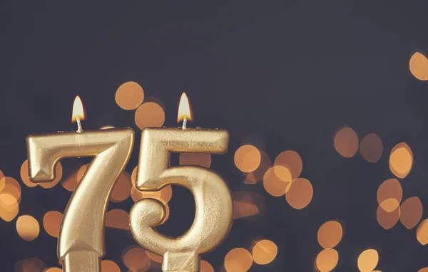 Золотий номер 75 святкування свічка на фоні розмитого світла — стокове фото